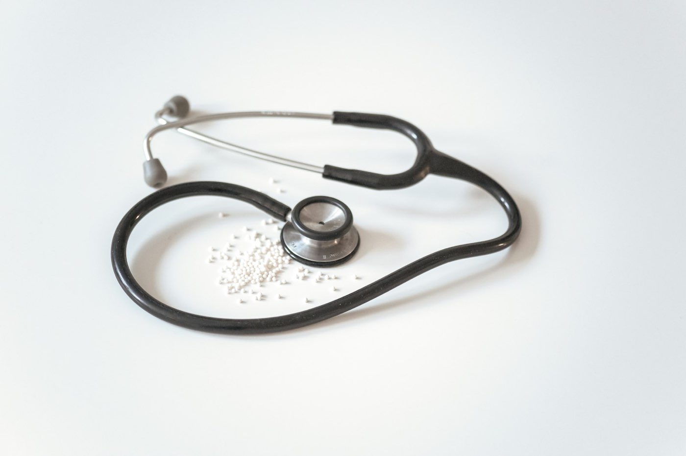 A black stethoscope lying on a plain white surface